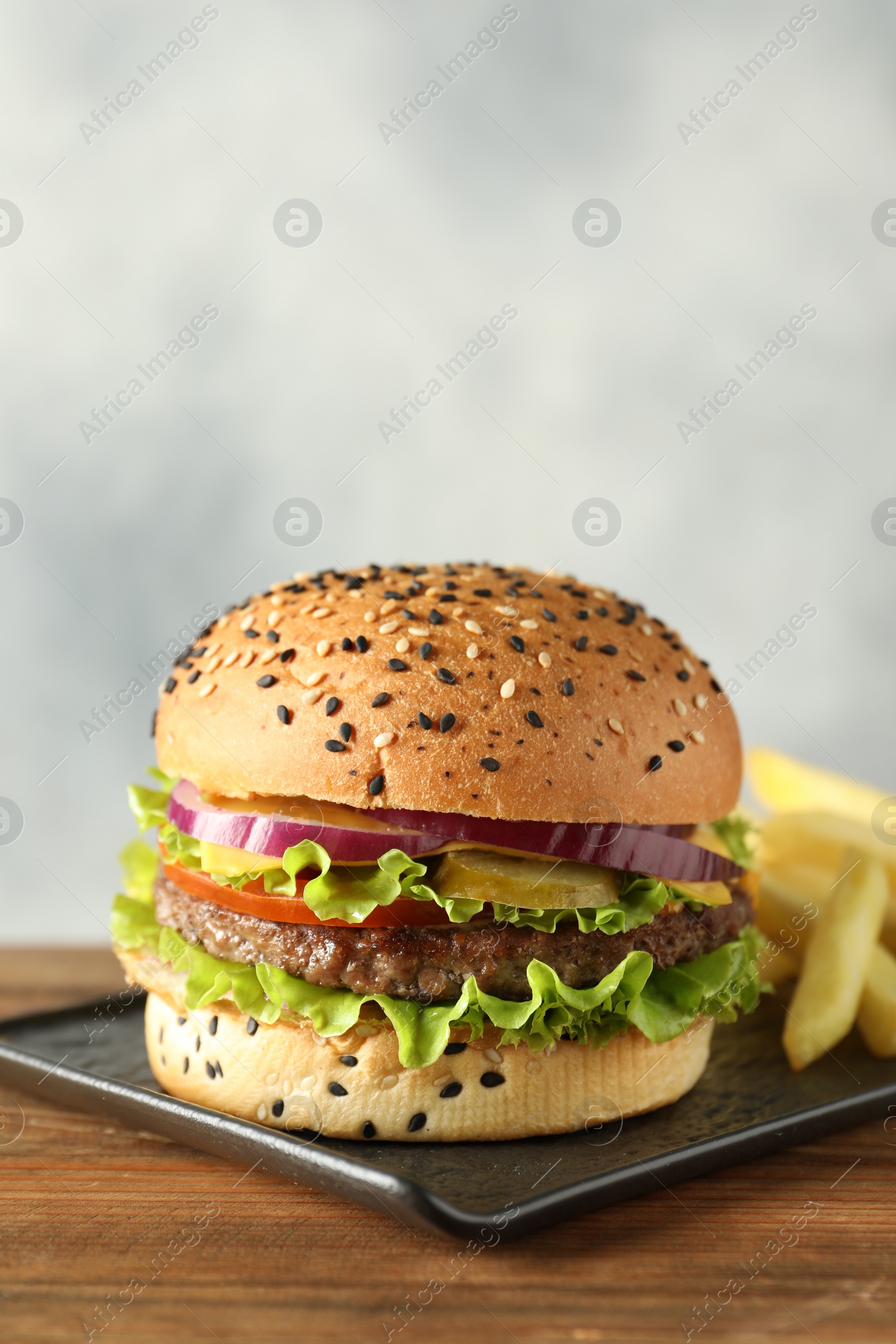 Burger with delicious patty and french fries on wooden table, space for text Photo of Burger with delicious patty and french fries on wooden table, space for text