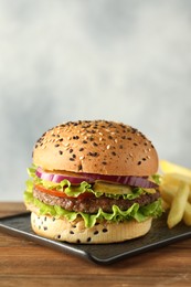 Photo of Burger with delicious patty and french fries on wooden table, space for text
