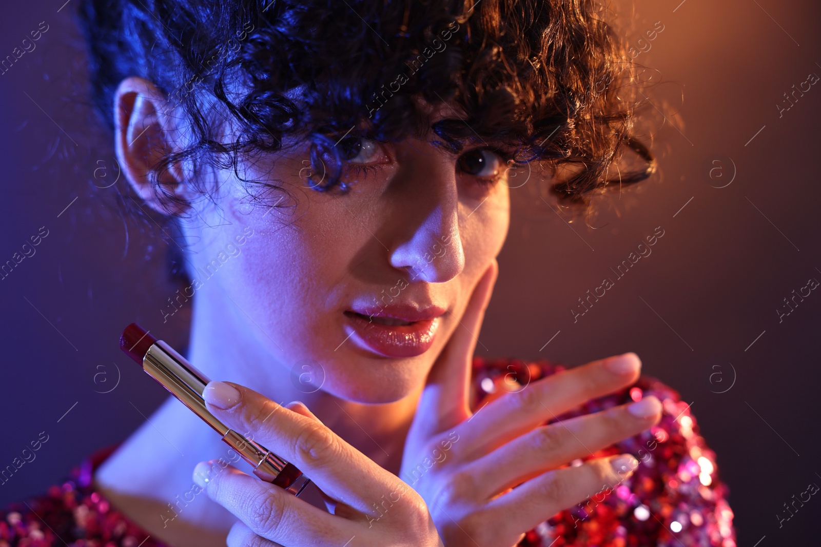 Photo of Beautiful young woman with lipstick posing on color background in neon lights