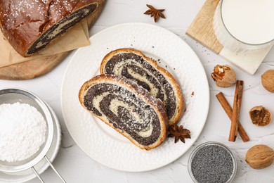 Flat lay composition with slices of poppy seed roll on white textured table. Tasty cake