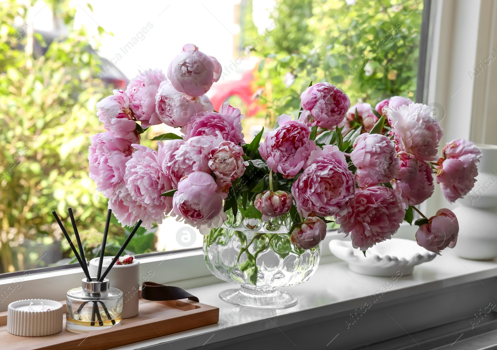 Photo of Beautiful pink peonies in vase on window sill. Interior design