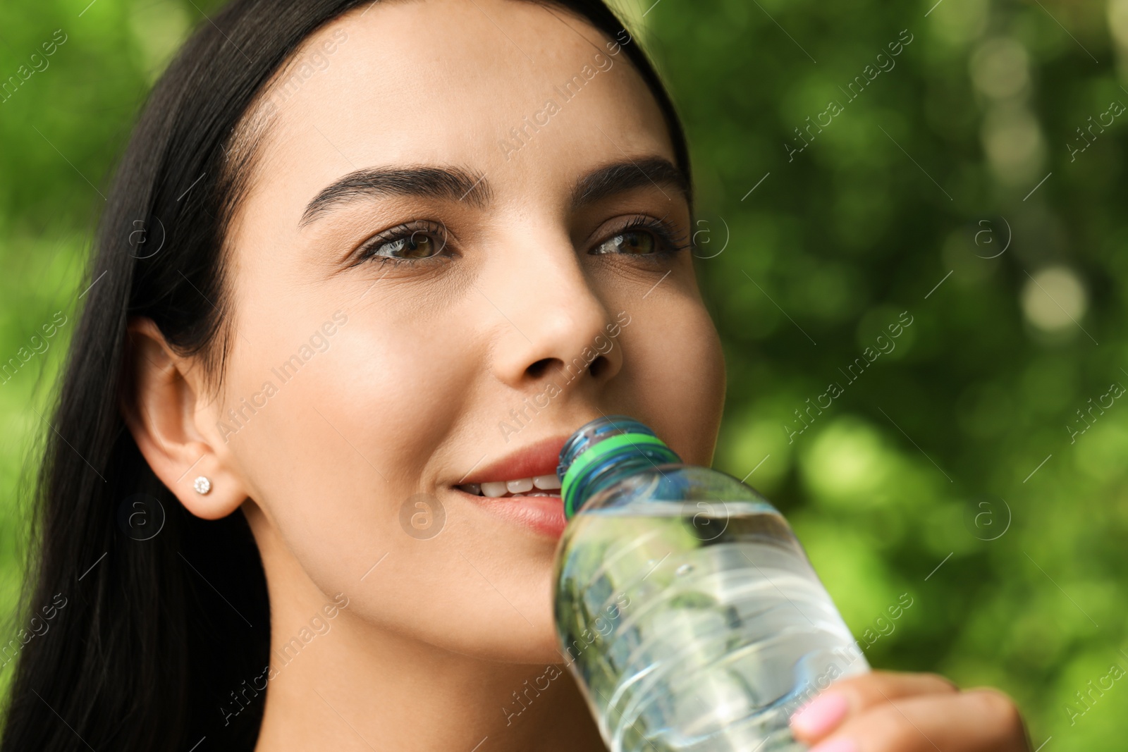 Photo of Young woman drinking water outdoors, closeup/ Refreshing drink