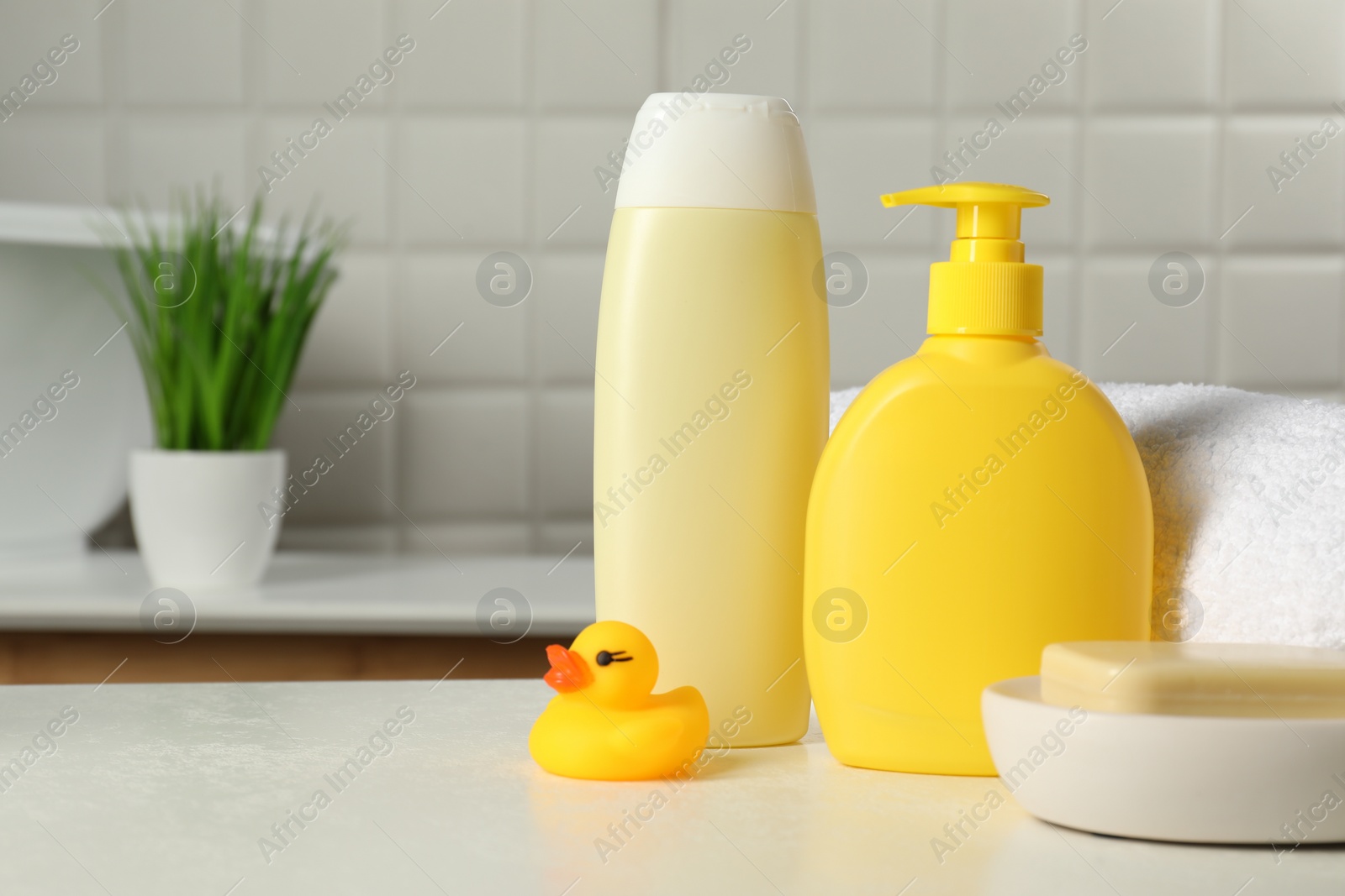 Photo of Baby cosmetic products, bath duck and towel on white table. Space for text