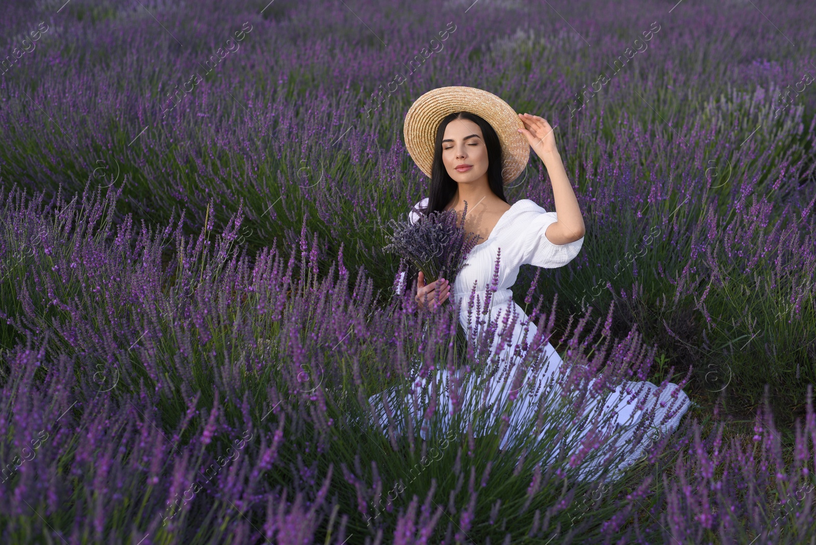 Photo of Beautiful young woman sitting in lavender field