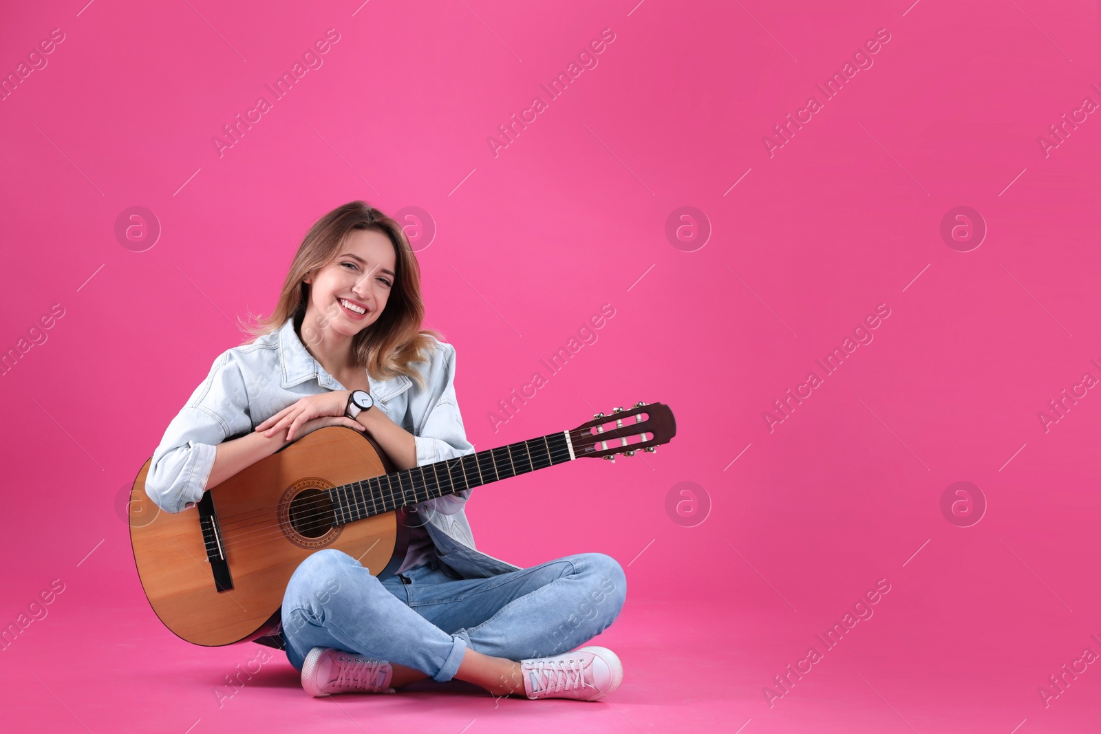Photo of Young woman with acoustic guitar on color background. Space for text