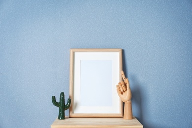 Photo of Mockup of blank frame and wooden hand on table