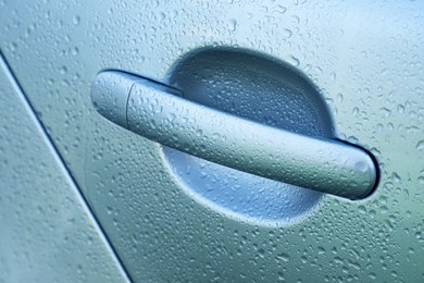 Closeup view of car door handle with water drops