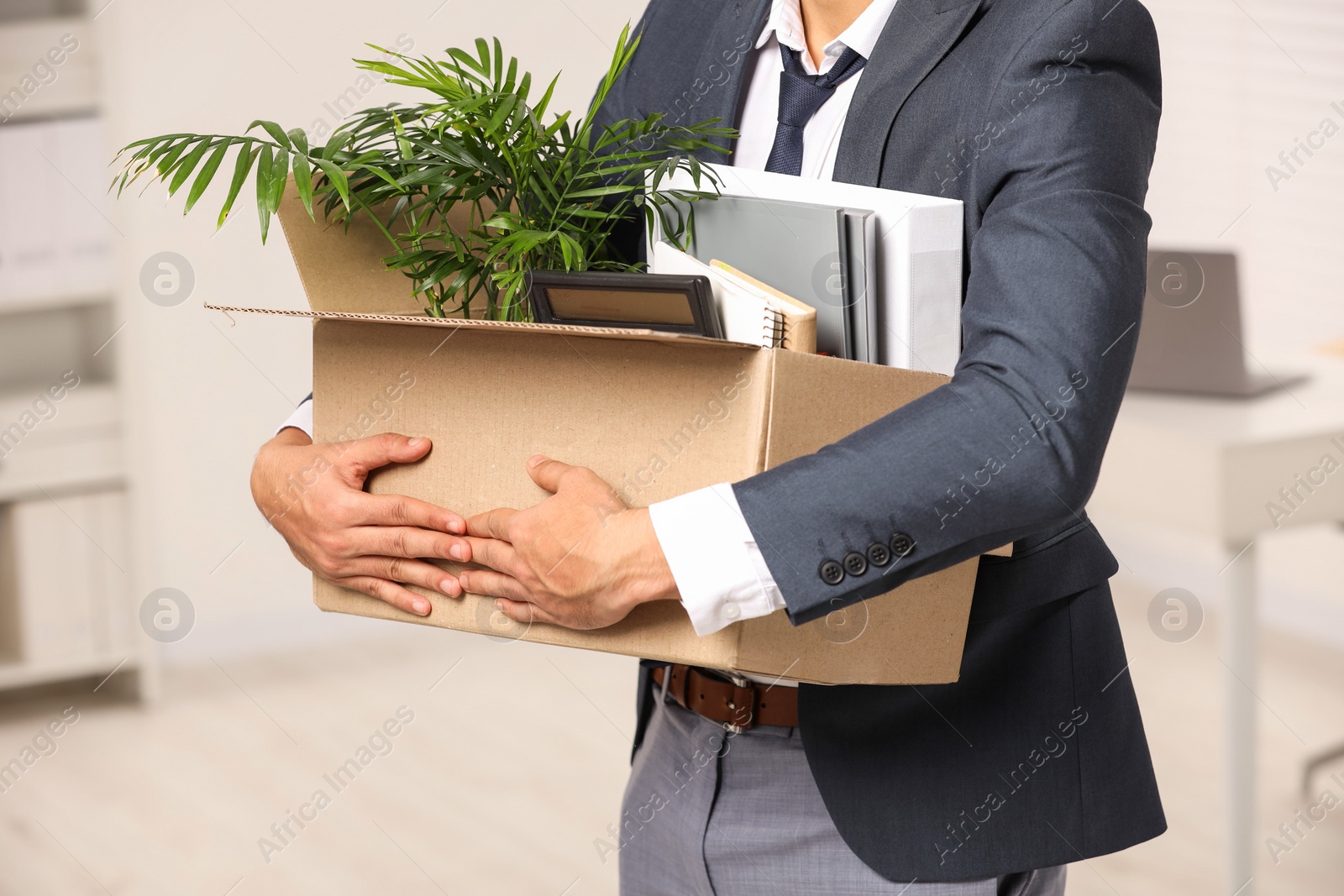 Photo of Unemployment problem. Man with box of personal belongings in office, closeup