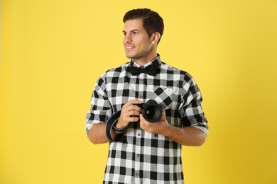 Photo of Professional photographer working on yellow background in studio