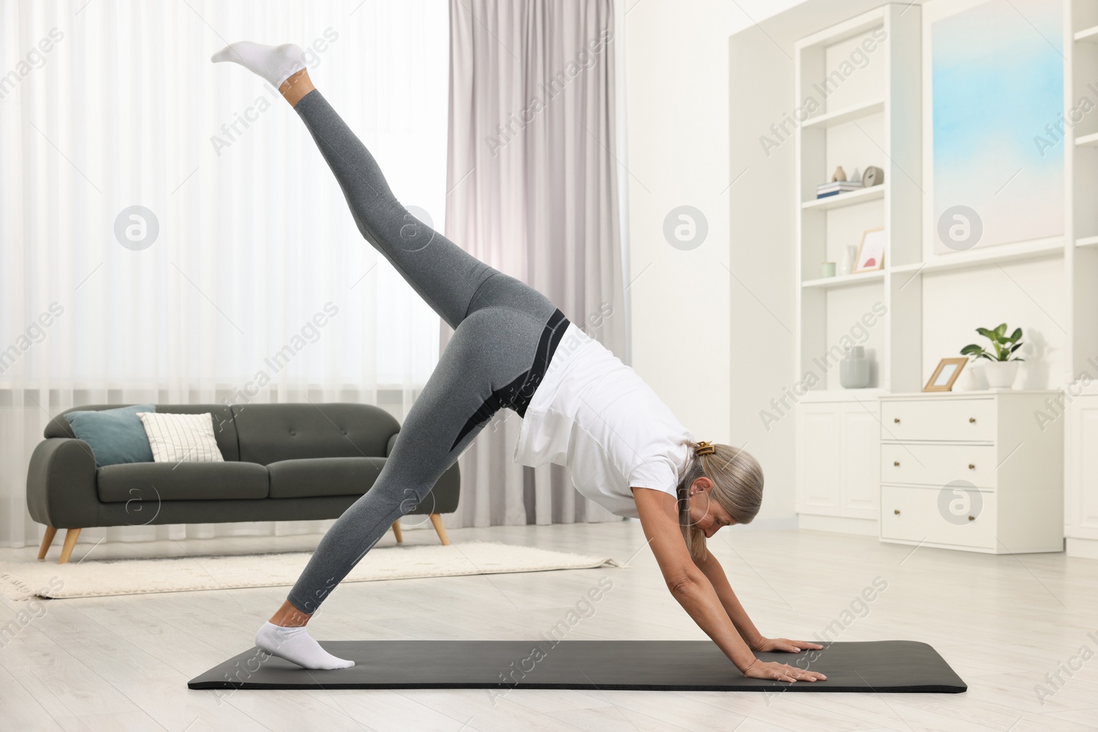 Photo of Senior woman practicing yoga on mat at home