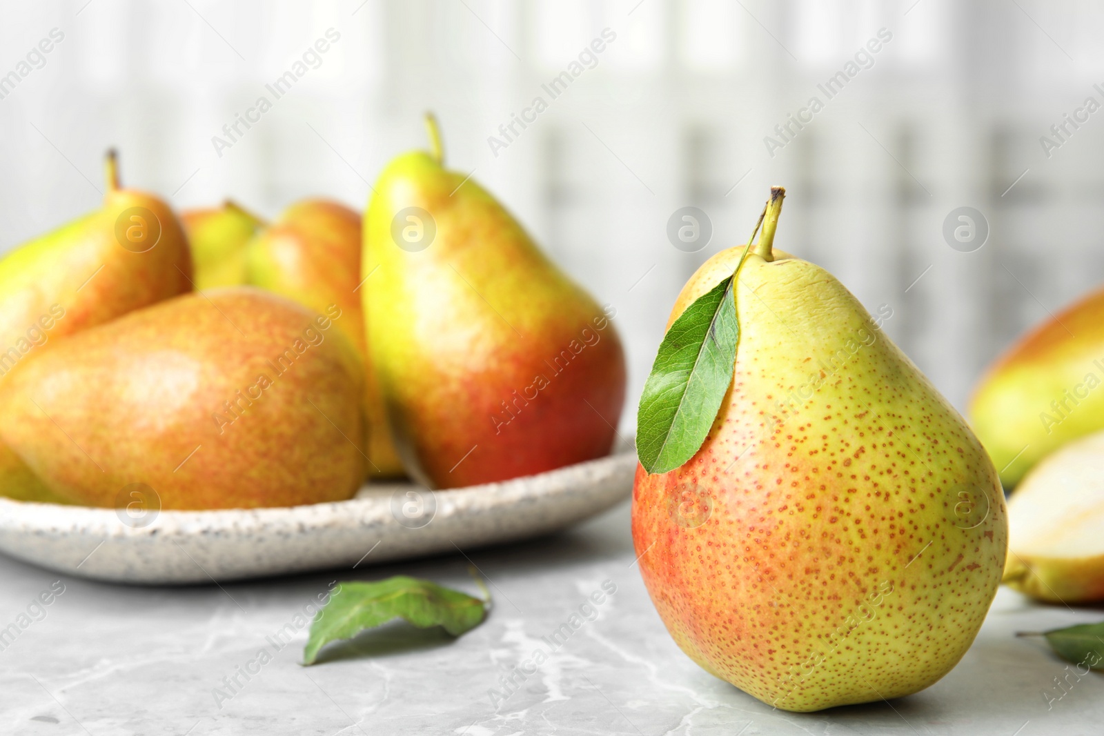 Photo of Ripe juicy pears on grey stone table against light background. Space for text