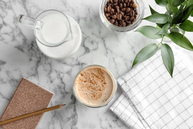 Photo of Glass of aromatic hot coffee, milk and beans on marble table, top view