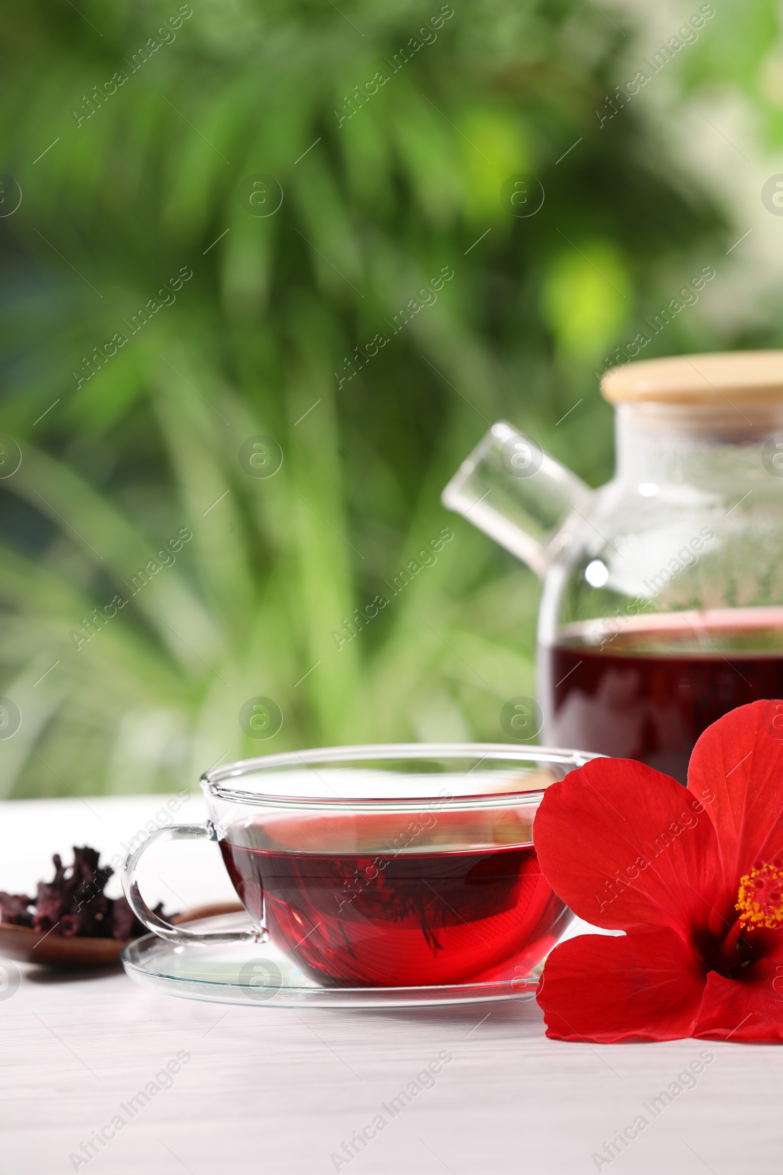 Photo of Delicious hibiscus tea and flowers on white wooden table outdoors, space for text