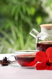 Delicious hibiscus tea and flowers on white wooden table outdoors, space for text