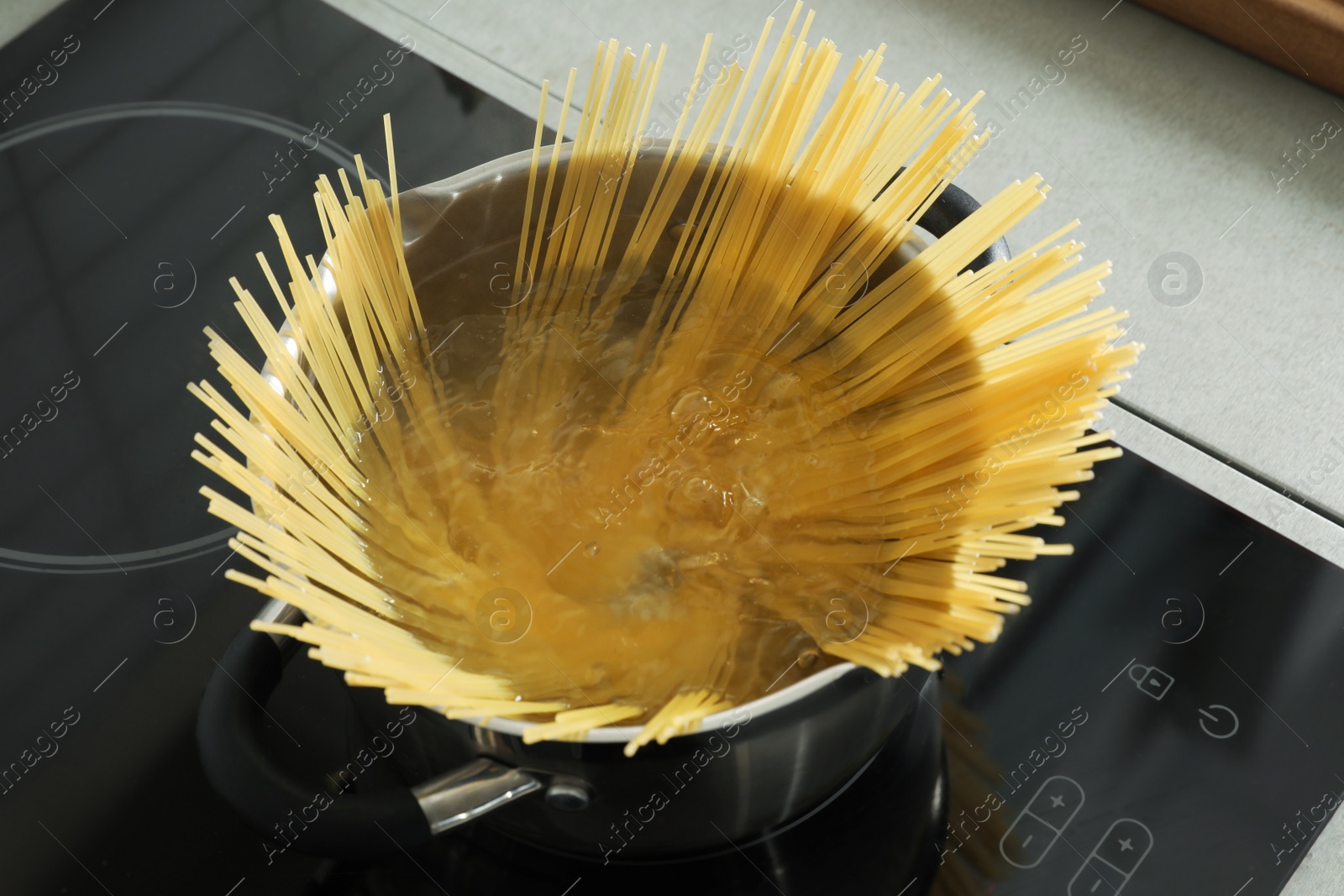 Photo of Cooking spaghetti in pot on electric stove