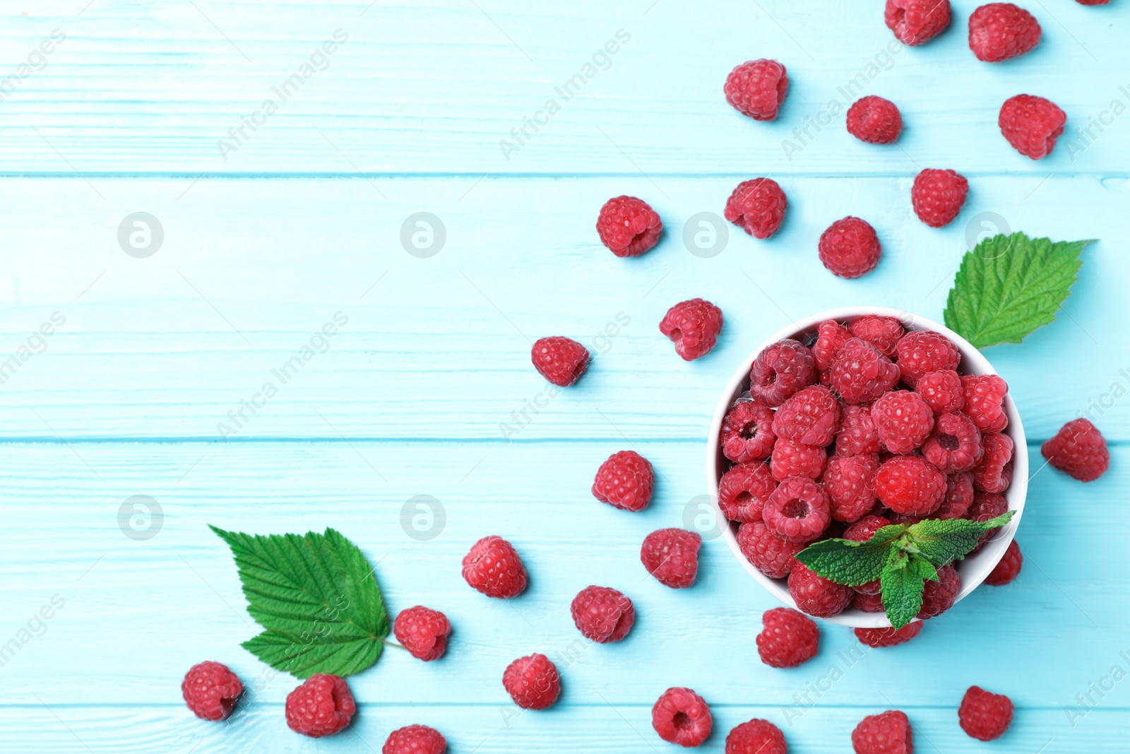 Photo of Bowl with ripe aromatic raspberries on wooden table, top view