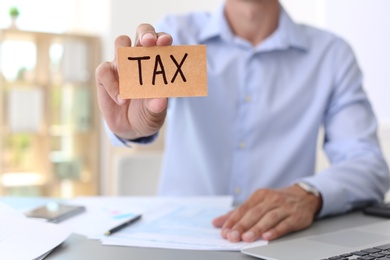 Man holding card with word TAX at table