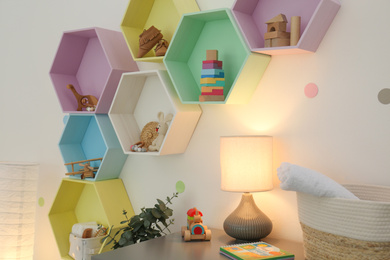 Photo of Bright colorful shelves on light wall in room. Interior design