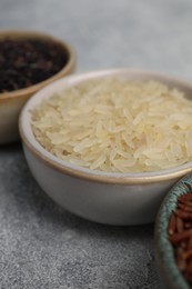 Photo of Bowls with different sorts of rice on grey table, closeup