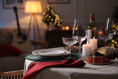 Photo of Christmas table setting with burning candles, appetizers and dishware. Space for text
