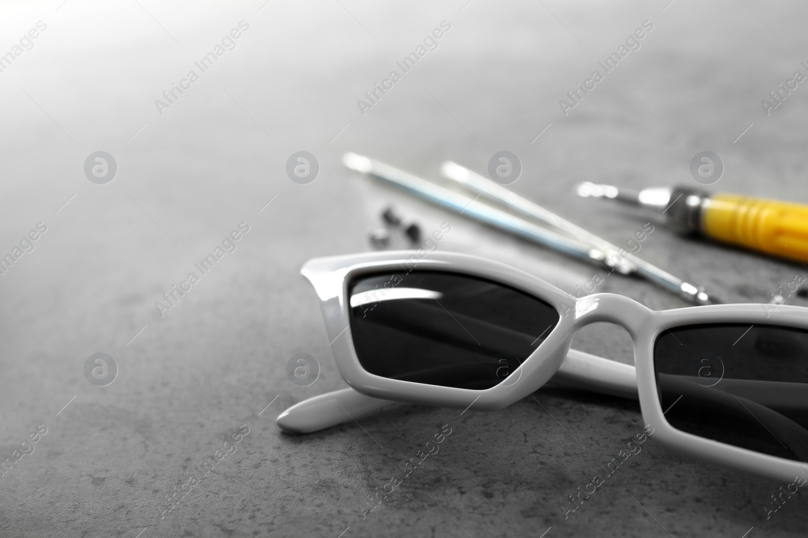 Photo of Stylish female sunglasses and fixing tools on grey table