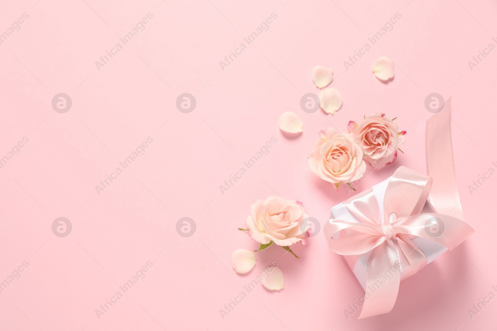 Photo of Happy Mother's Day. Beautiful flowers and gift box on pink background, flat lay. Space for text