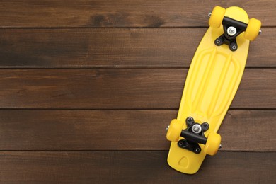 Photo of Yellow skateboard on wooden background, top view. Space for text