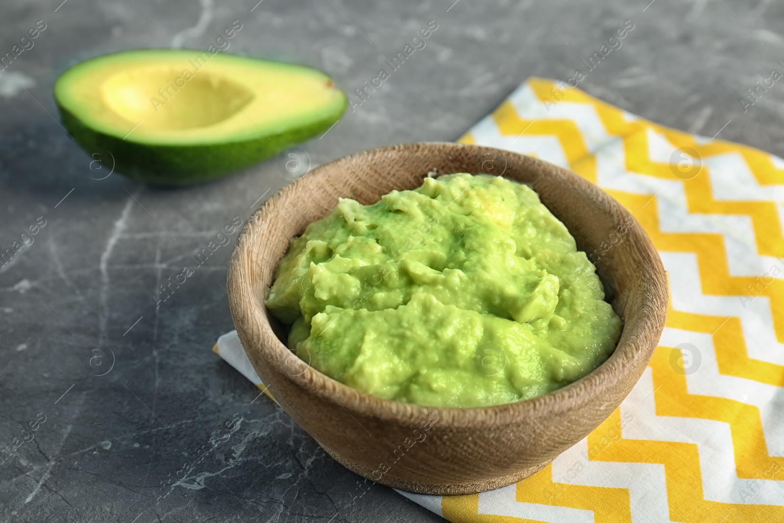 Photo of Bowl with guacamole made of ripe avocados on table