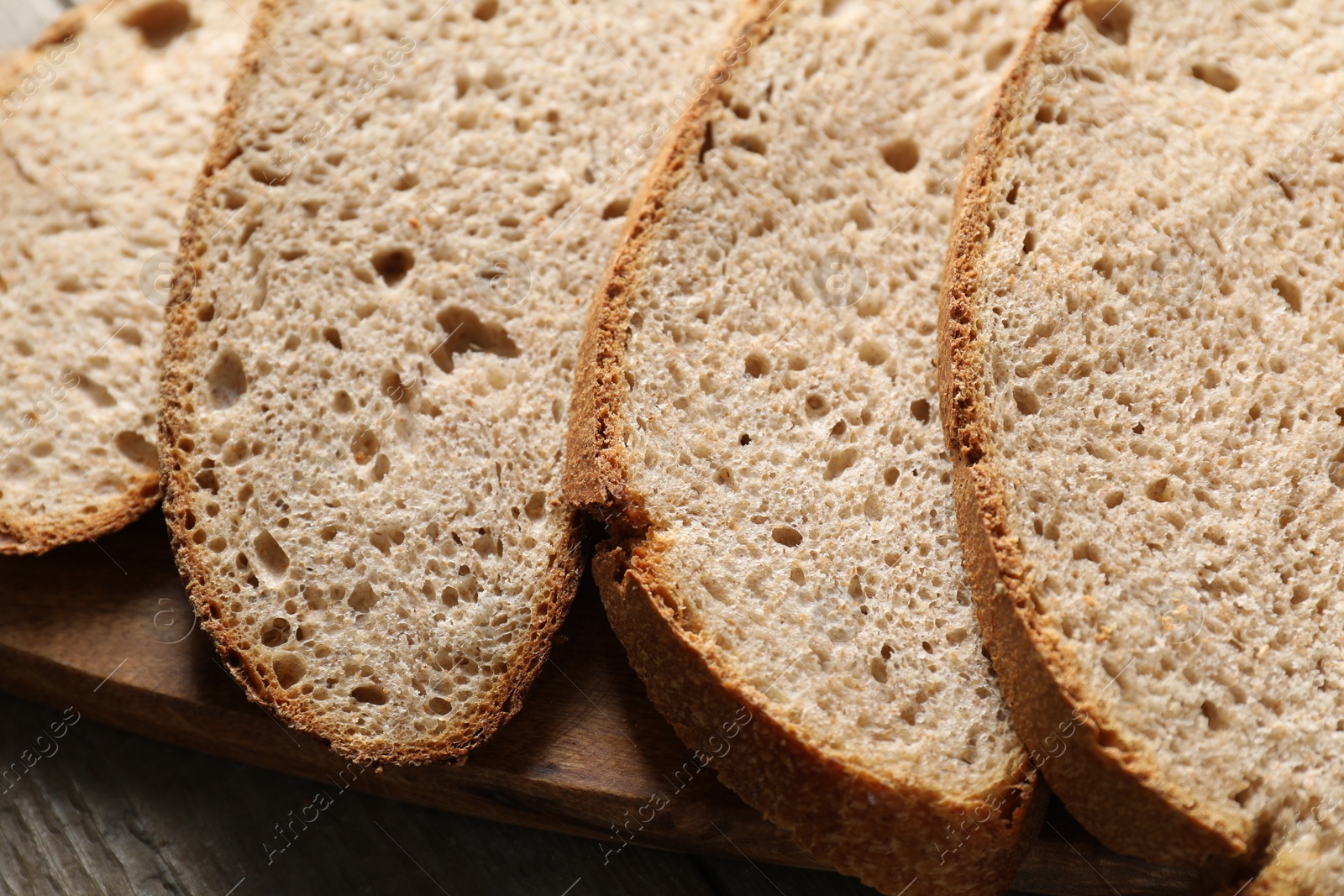 Photo of Freshly baked cut sourdough bread on wooden table, closeup