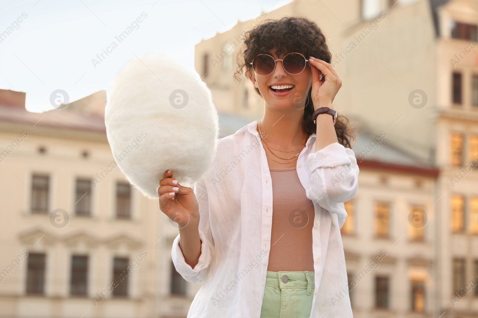 Photo of Smiling woman with cotton candy on city street