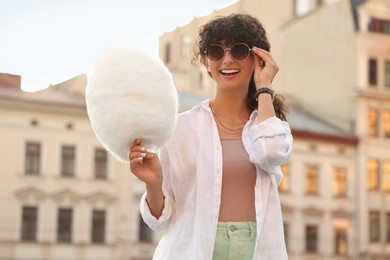 Smiling woman with cotton candy on city street