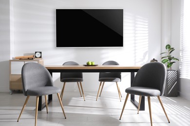 Image of Modern wide screen TV on white wall in room with stylish furniture 