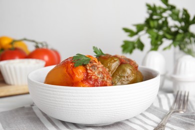 Delicious stuffed peppers with parsley in bowl on table