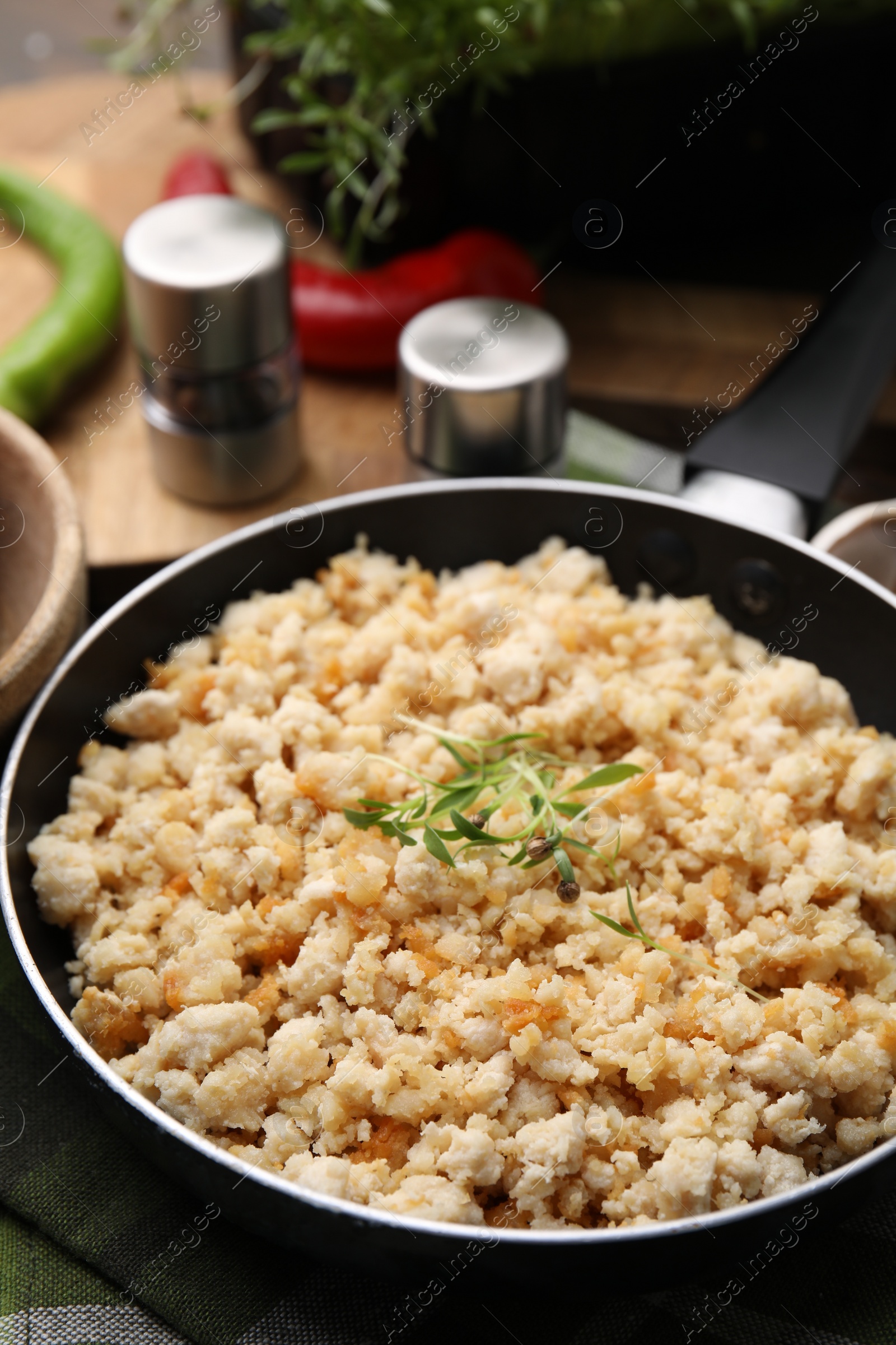 Photo of Fried ground meat in frying pan and microgreens on table, closeup