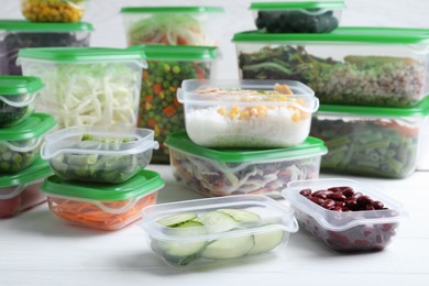 Set of plastic containers with fresh food on white wooden table