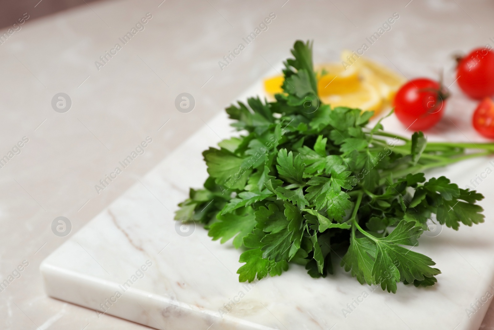 Photo of Stone board with fresh green parsley on table, closeup