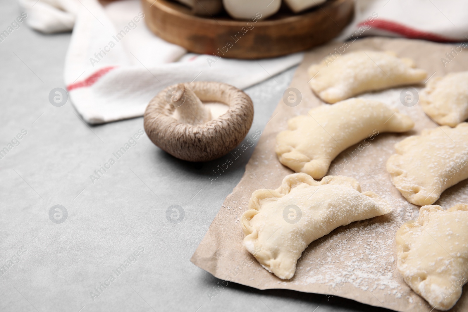 Photo of Raw dumplings (varenyky) with tasty filling on grey table, closeup and space for text. Traditional Ukrainian dish
