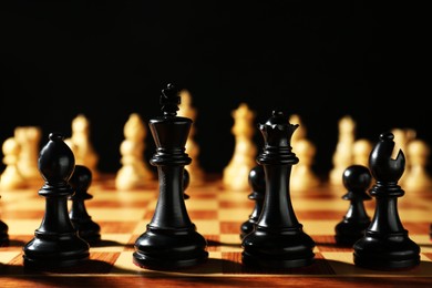 Chess pieces on wooden board against dark background. Competition concept