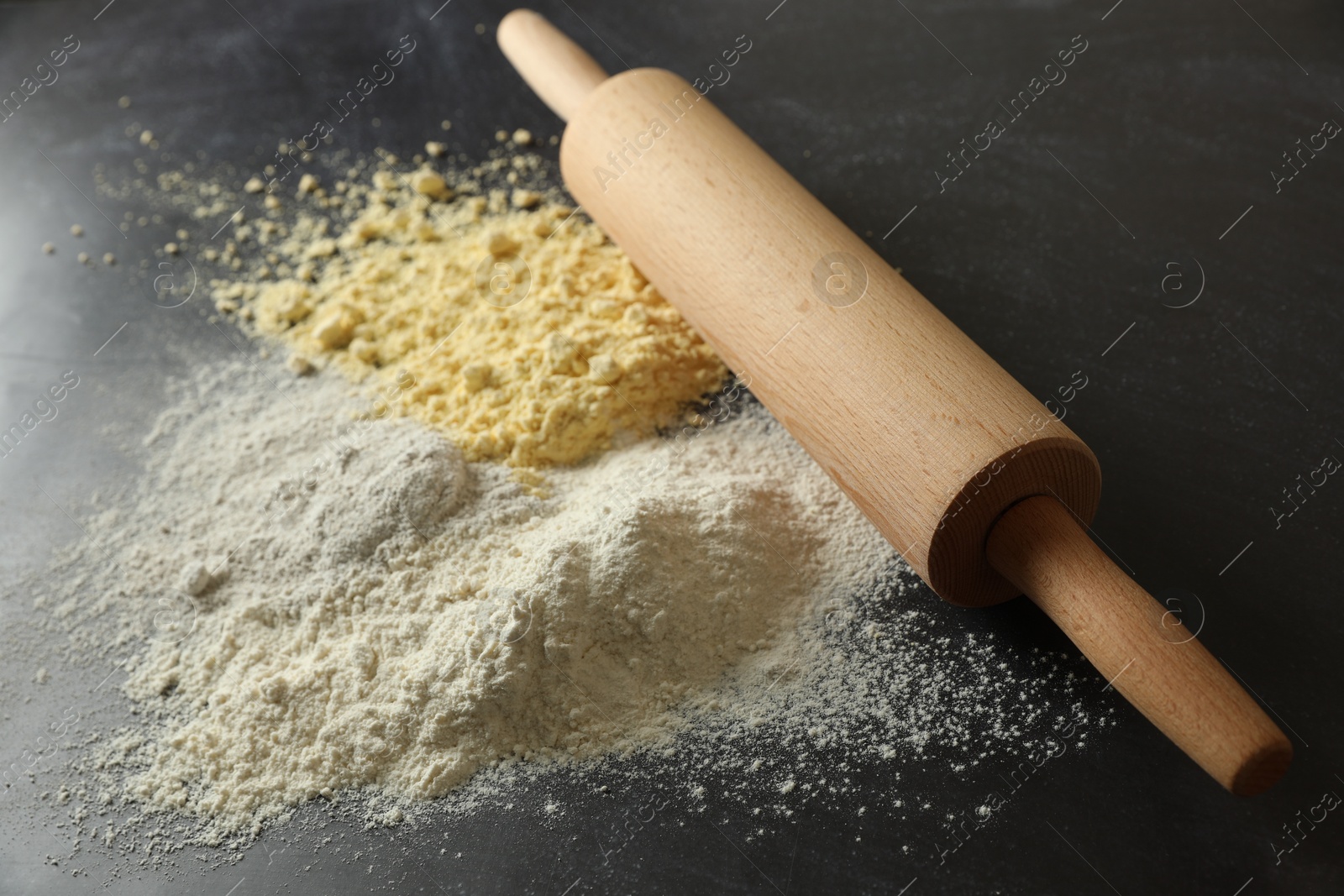 Photo of Rolling pin and different types of flour on black table