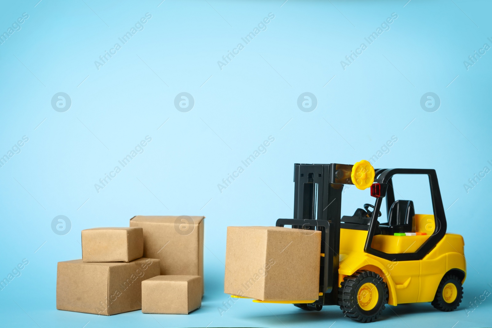 Photo of Toy forklift with boxes on blue background. Logistics and wholesale concept