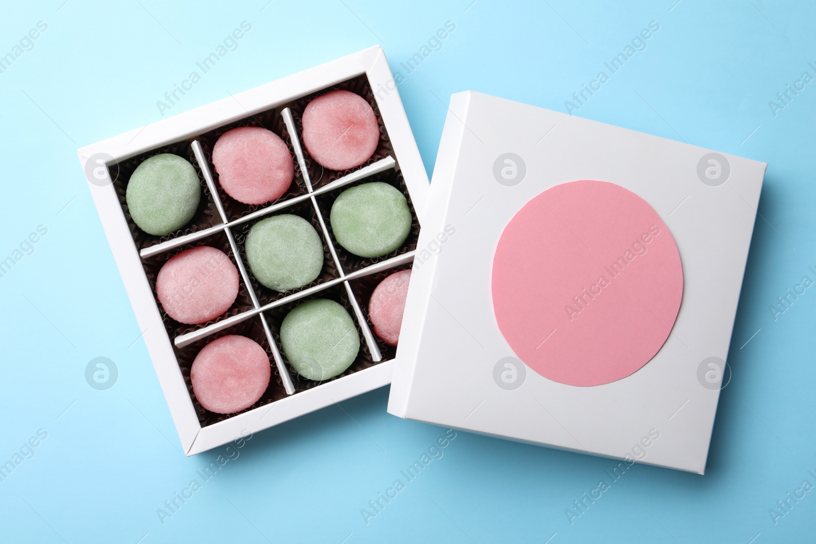 Photo of Many different delicious mochi in box on light blue background, top view. Traditional Japanese dessert