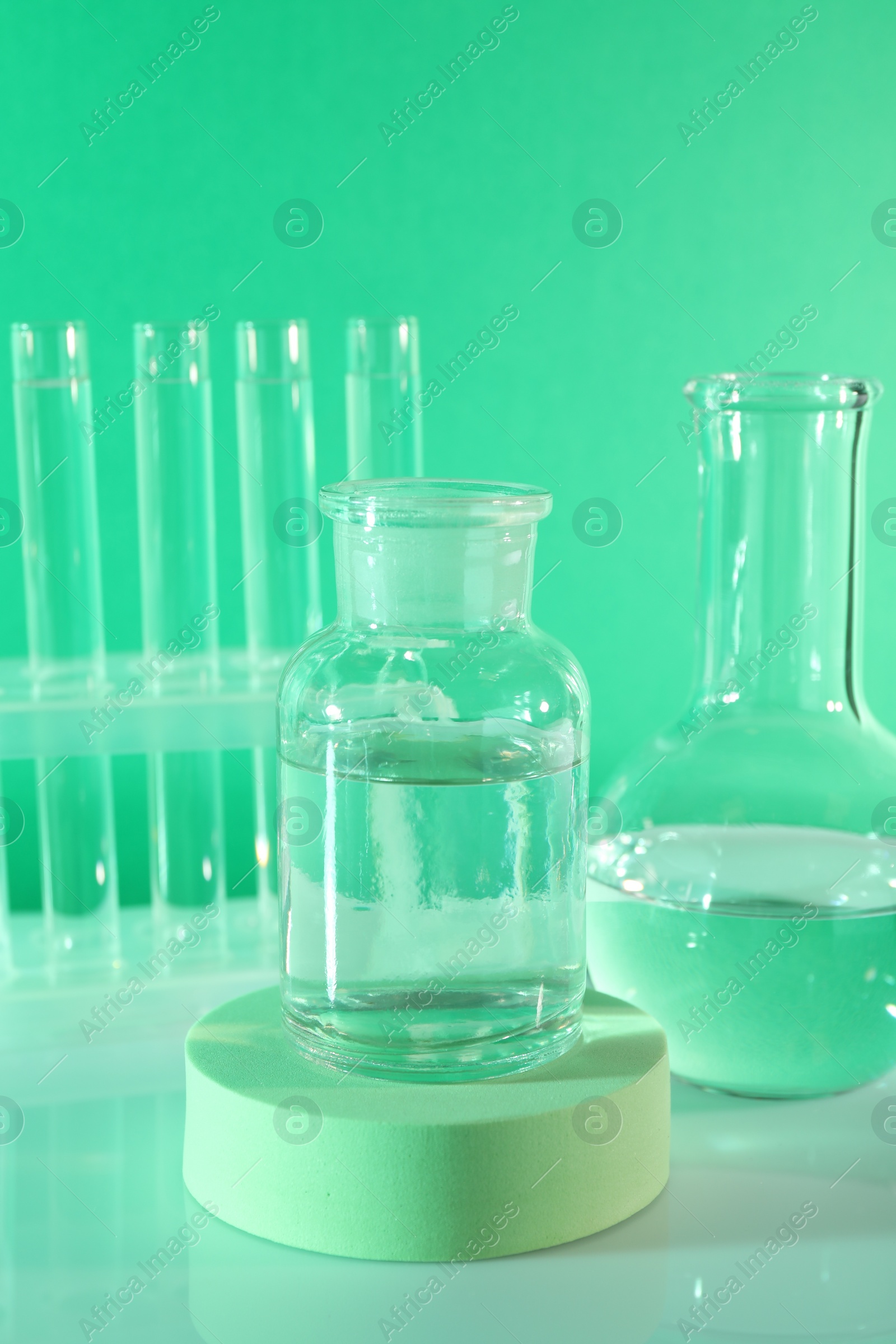 Photo of Laboratory analysis. Glass flasks and test tubes on table against green background