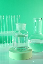 Laboratory analysis. Glass flasks and test tubes on table against green background