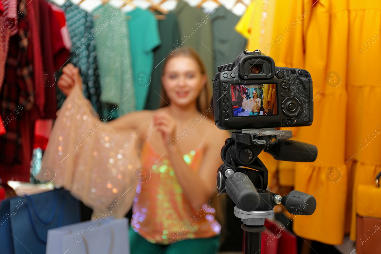 Photo of Fashion blogger recording new video in wardrobe, focus on camera