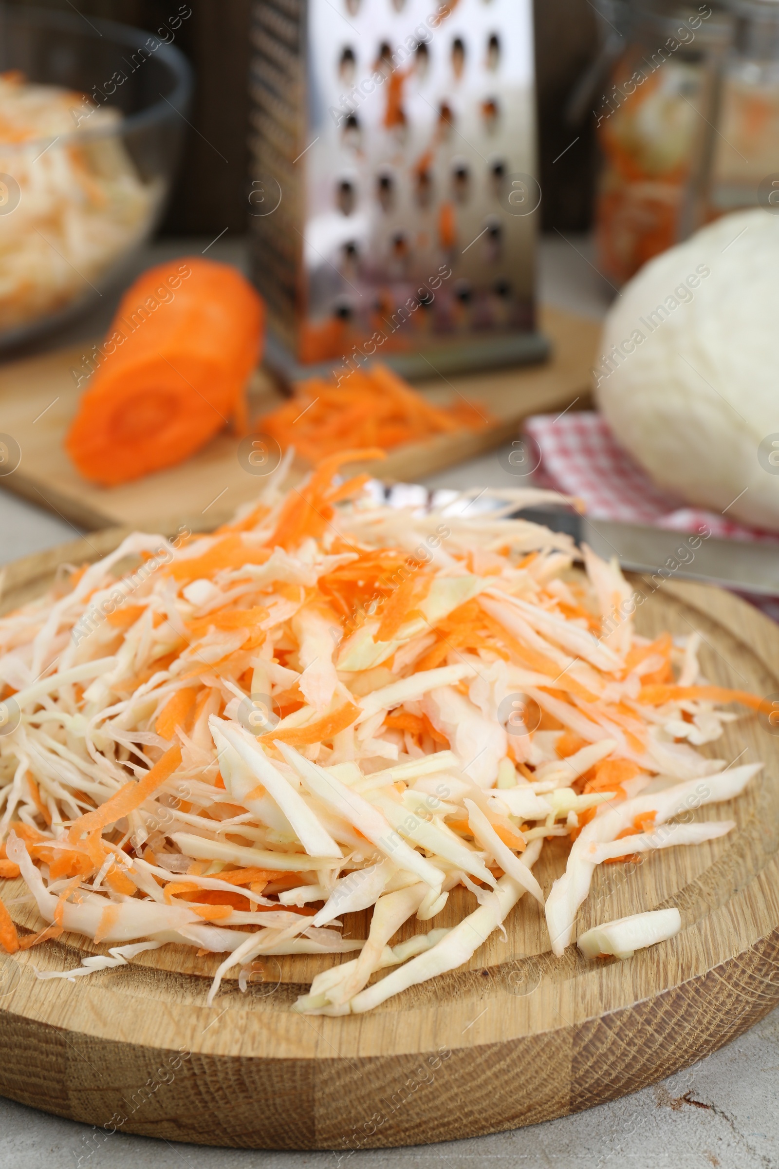 Photo of Cooking delicious sauerkraut soup. Fresh chopped carrot and cabbage on table, closeup