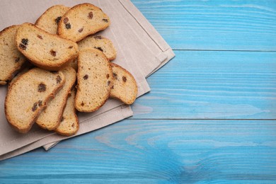 Photo of Sweet hard chuck crackers with raisins on light blue wooden table, flat lay. Space for text