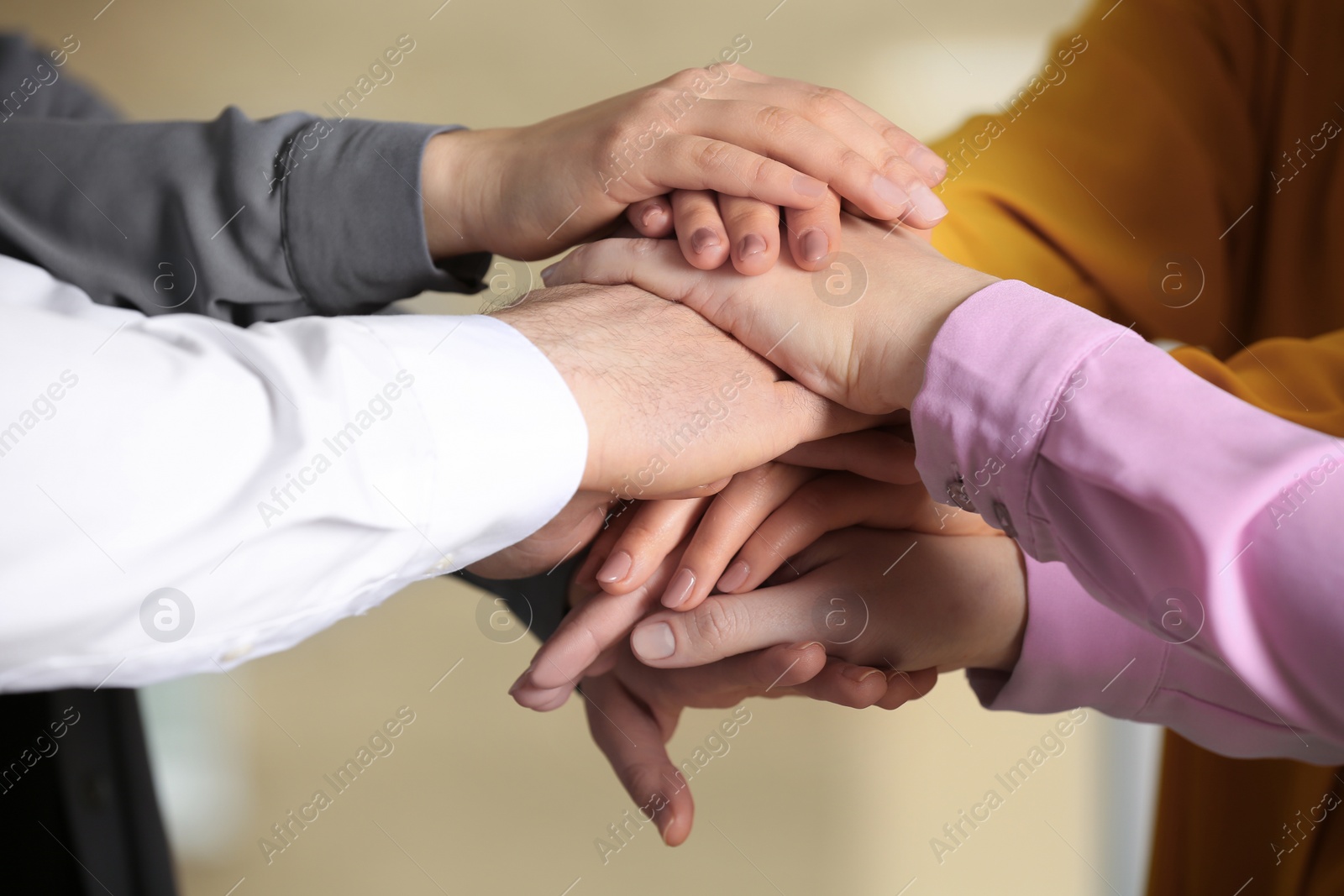 Photo of Young people putting their hands together on blurred background, closeup