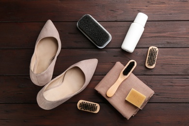 Stylish footwear with shoe care accessories on brown wooden table, flat lay