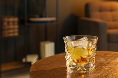 Photo of Glass of whiskey on wooden table in room, space for text. Relax at home