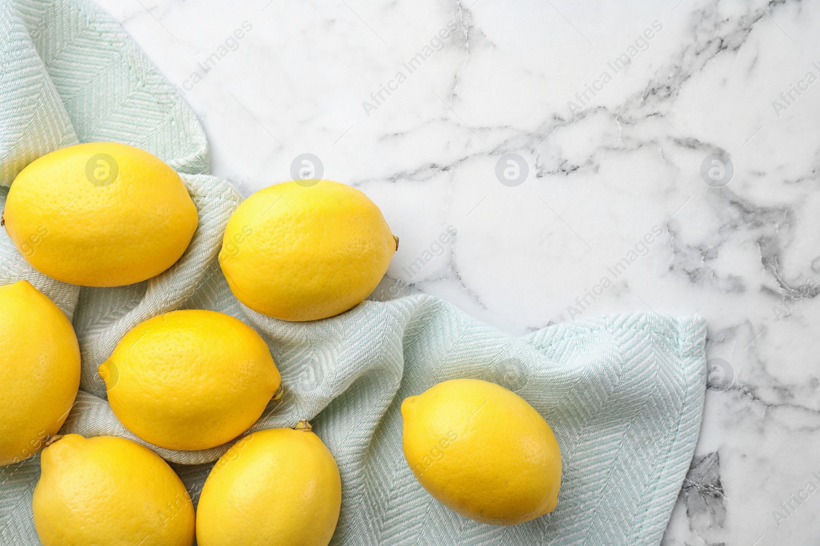 Photo of Fresh lemons and leaf on white marble table, top view. Space for table